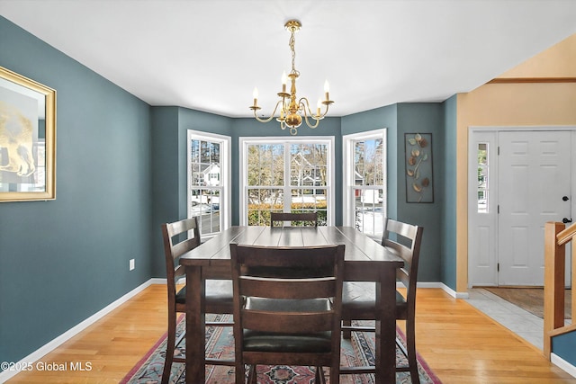 dining area with baseboards, a chandelier, and light wood finished floors