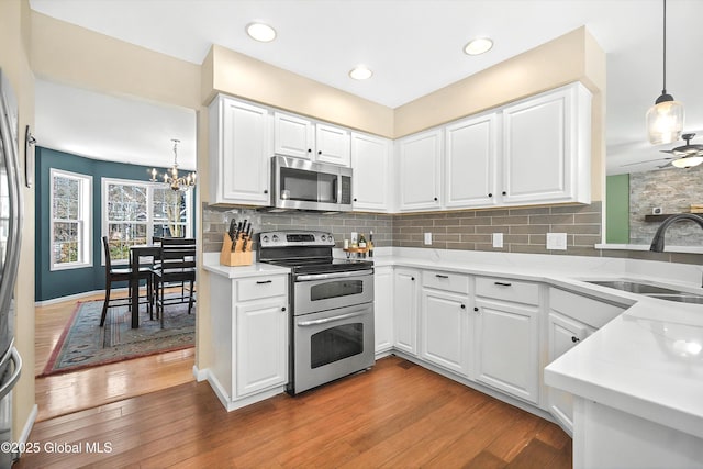 kitchen featuring light wood-style floors, tasteful backsplash, appliances with stainless steel finishes, and a sink