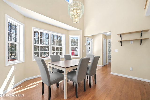 dining area featuring a wealth of natural light, baseboards, light wood-style floors, and an inviting chandelier