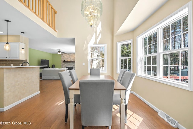 dining room with visible vents, light wood-style flooring, a fireplace, and baseboards