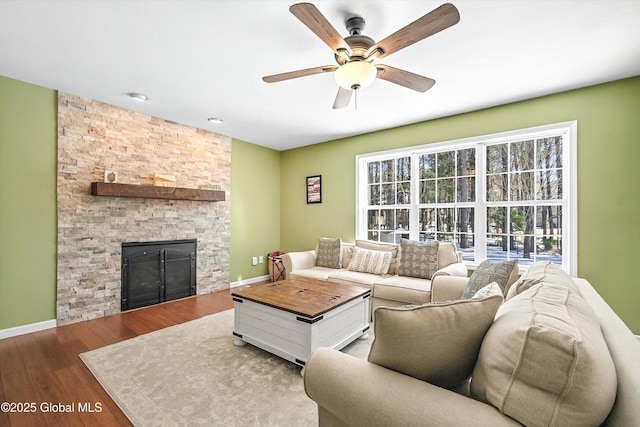 living room with a ceiling fan, wood finished floors, a fireplace, and baseboards