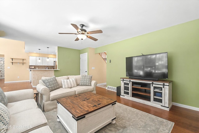 living room with visible vents, baseboards, wood finished floors, and a ceiling fan