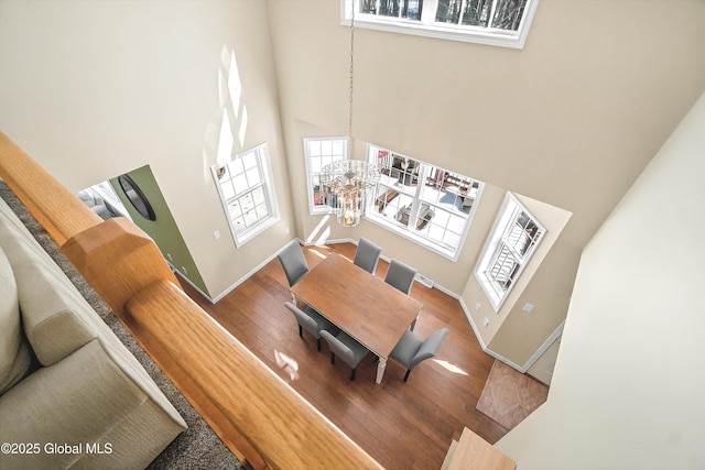 living area featuring wood finished floors, plenty of natural light, a chandelier, and a towering ceiling