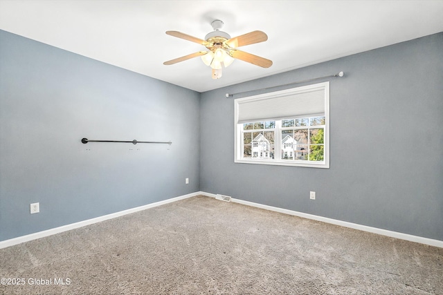 carpeted spare room with visible vents, baseboards, and ceiling fan