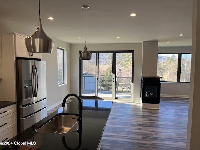 kitchen with dark wood-style flooring, a sink, white cabinets, dark countertops, and stainless steel fridge