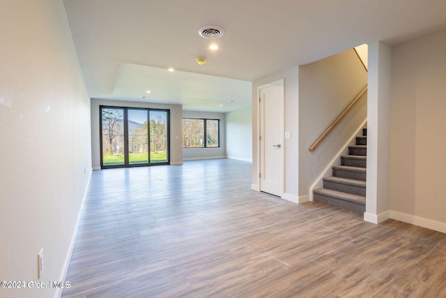 unfurnished living room featuring stairs, recessed lighting, wood finished floors, and baseboards