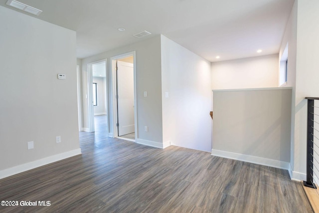 unfurnished room with dark wood-style floors, visible vents, and baseboards