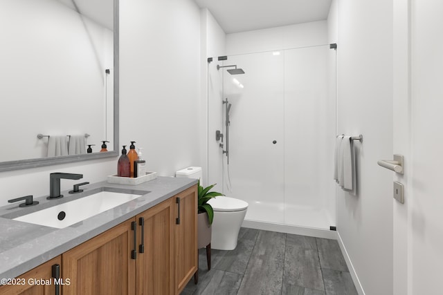 bathroom with a stall shower, vanity, toilet, and wood finished floors