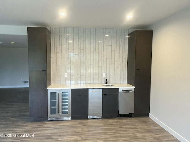 bar featuring dark wood-style floors, wine cooler, a sink, and baseboards