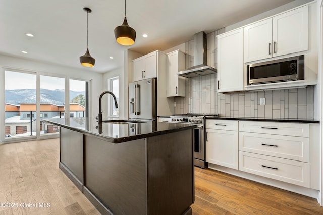 kitchen featuring decorative light fixtures, stainless steel appliances, dark countertops, a mountain view, and wall chimney range hood