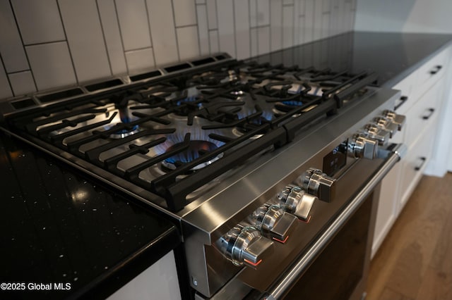 details featuring dark countertops, stainless steel gas range, and white cabinetry