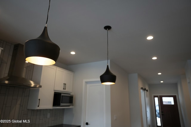 room details featuring extractor fan, recessed lighting, white cabinets, tasteful backsplash, and stainless steel microwave