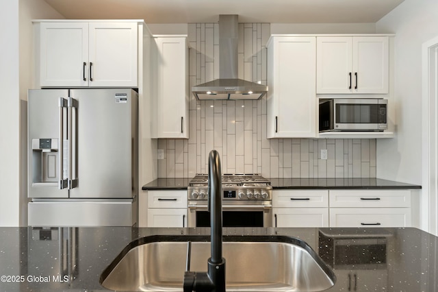 kitchen featuring wall chimney exhaust hood, high end appliances, dark countertops, and white cabinetry