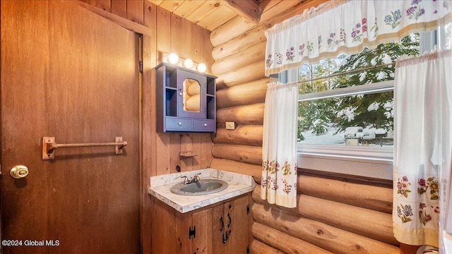 bathroom featuring beamed ceiling, rustic walls, wood ceiling, and sink