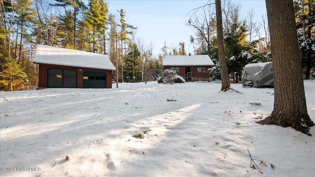 yard covered in snow with a garage and an outdoor structure