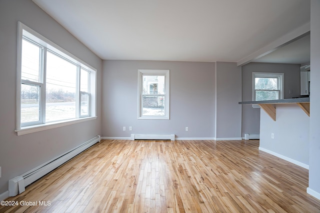 spare room with a baseboard radiator, a wealth of natural light, and light hardwood / wood-style floors