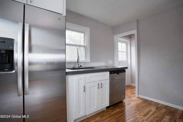 kitchen featuring appliances with stainless steel finishes, white cabinetry, a wealth of natural light, and sink