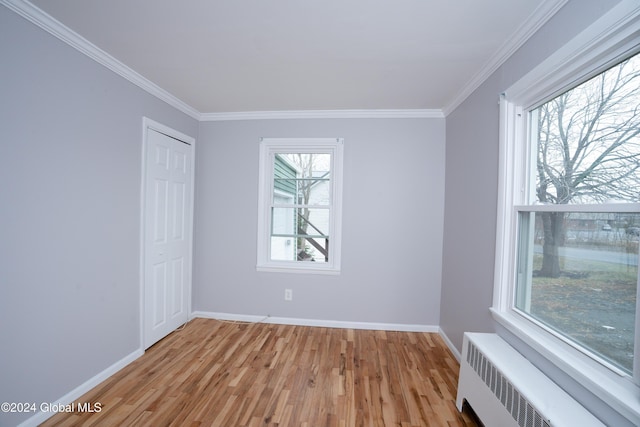 unfurnished room featuring ornamental molding, radiator, and light hardwood / wood-style flooring