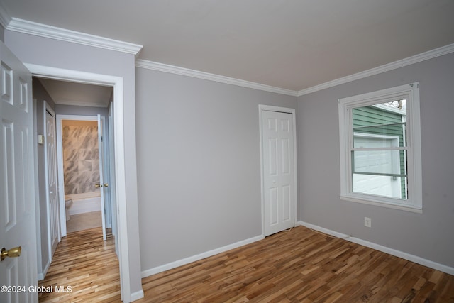 empty room featuring light wood-type flooring and ornamental molding