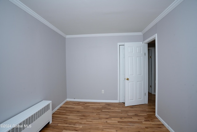 spare room with light hardwood / wood-style floors, radiator heating unit, and ornamental molding