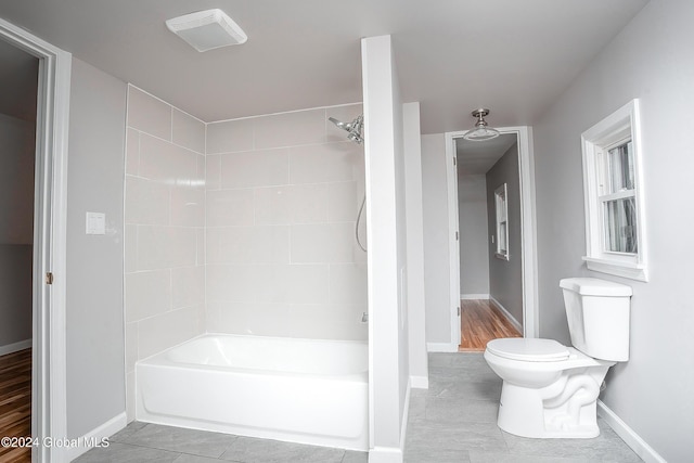 bathroom with tiled shower / bath combo and toilet