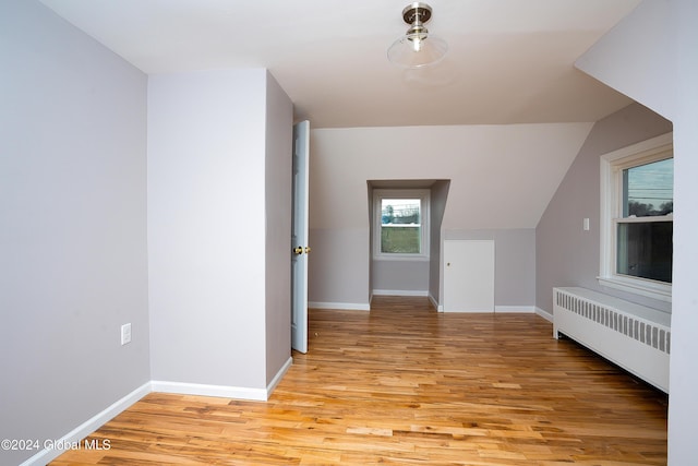 bonus room with lofted ceiling, light hardwood / wood-style floors, and radiator heating unit