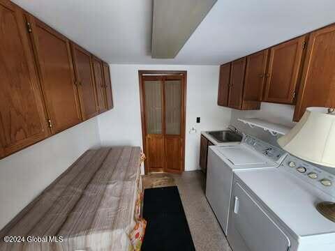 clothes washing area featuring cabinets, sink, and washing machine and clothes dryer