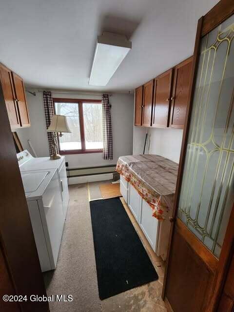 bedroom featuring washing machine and dryer, light carpet, and a baseboard heating unit