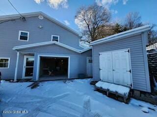 snow covered back of property with a garage