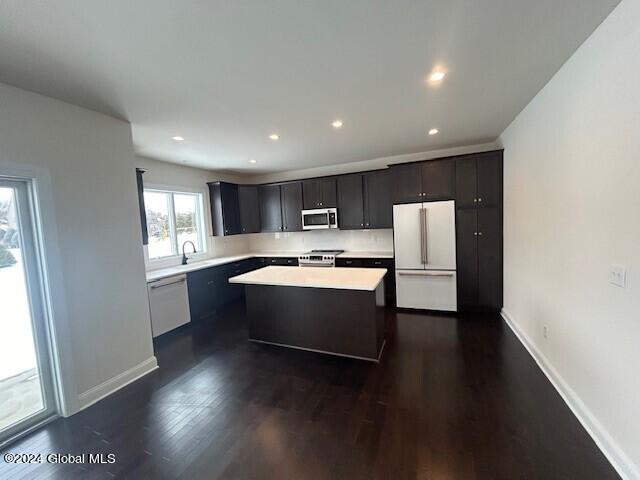 kitchen with sink, a center island, dark hardwood / wood-style floors, and appliances with stainless steel finishes