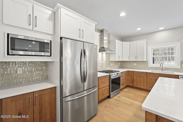 kitchen featuring wall chimney exhaust hood, stainless steel appliances, sink, and white cabinets