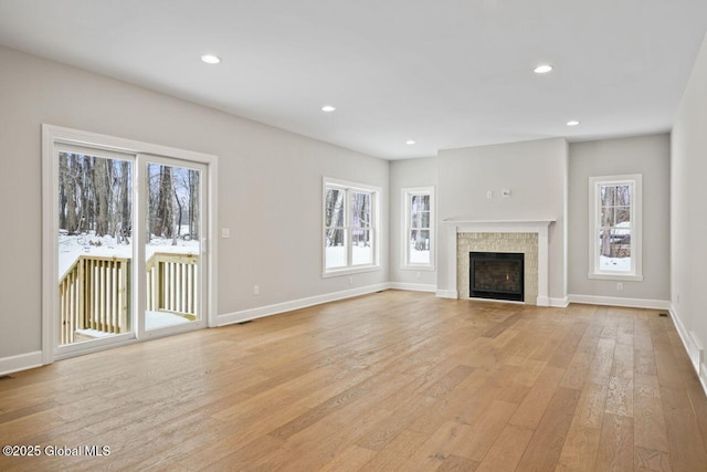 unfurnished living room featuring a tiled fireplace and light hardwood / wood-style flooring