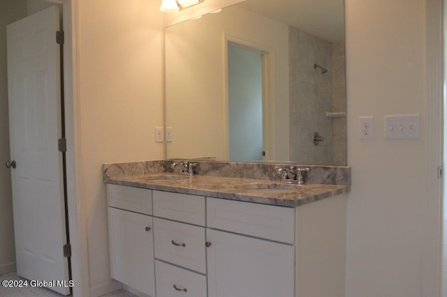 bathroom with a tile shower and vanity