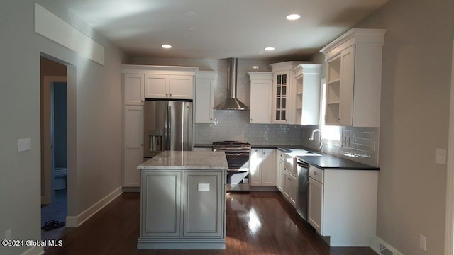 kitchen featuring white cabinets, a kitchen island, wall chimney exhaust hood, and appliances with stainless steel finishes