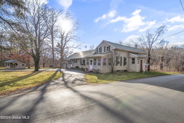 view of front of property featuring a front lawn and a storage shed