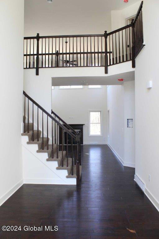 stairs featuring wood-type flooring and a towering ceiling