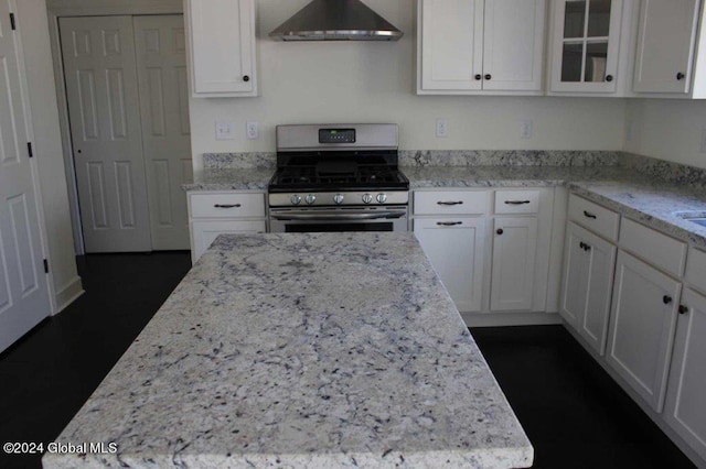 kitchen featuring white cabinetry, a center island, stainless steel gas stove, wall chimney exhaust hood, and light stone counters