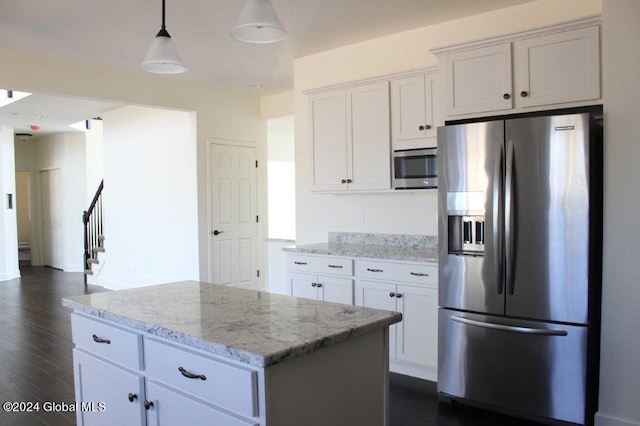 kitchen with stainless steel appliances, decorative light fixtures, white cabinets, a center island, and dark hardwood / wood-style floors