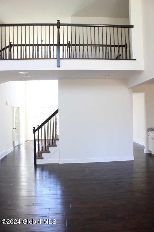 staircase with hardwood / wood-style floors and a high ceiling