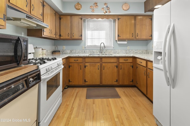 kitchen featuring white appliances, sink, and light hardwood / wood-style flooring