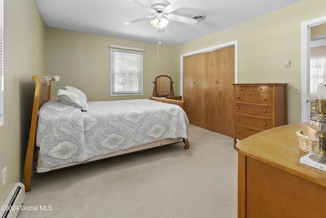 carpeted bedroom with ceiling fan, a closet, and a baseboard heating unit