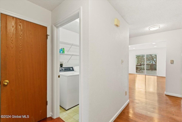 corridor with a textured ceiling and light hardwood / wood-style floors