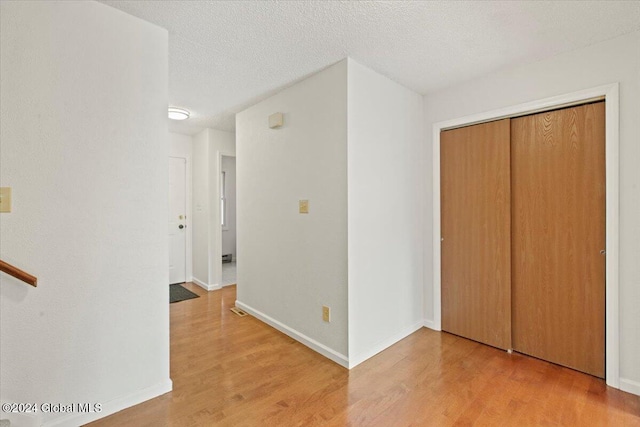 hall featuring a textured ceiling and light hardwood / wood-style floors