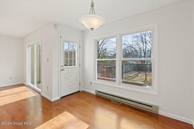 doorway featuring hardwood / wood-style floors, a textured ceiling, and a baseboard heating unit