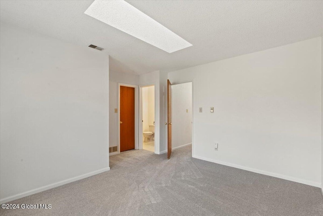 carpeted spare room with a textured ceiling and a skylight