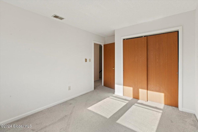 unfurnished bedroom featuring a closet and light colored carpet