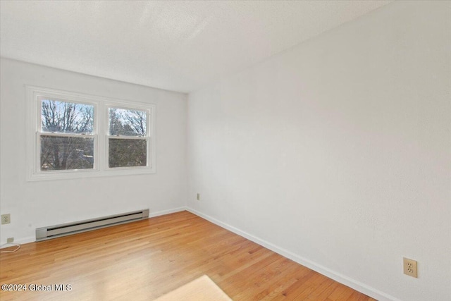 empty room featuring light wood-type flooring and baseboard heating