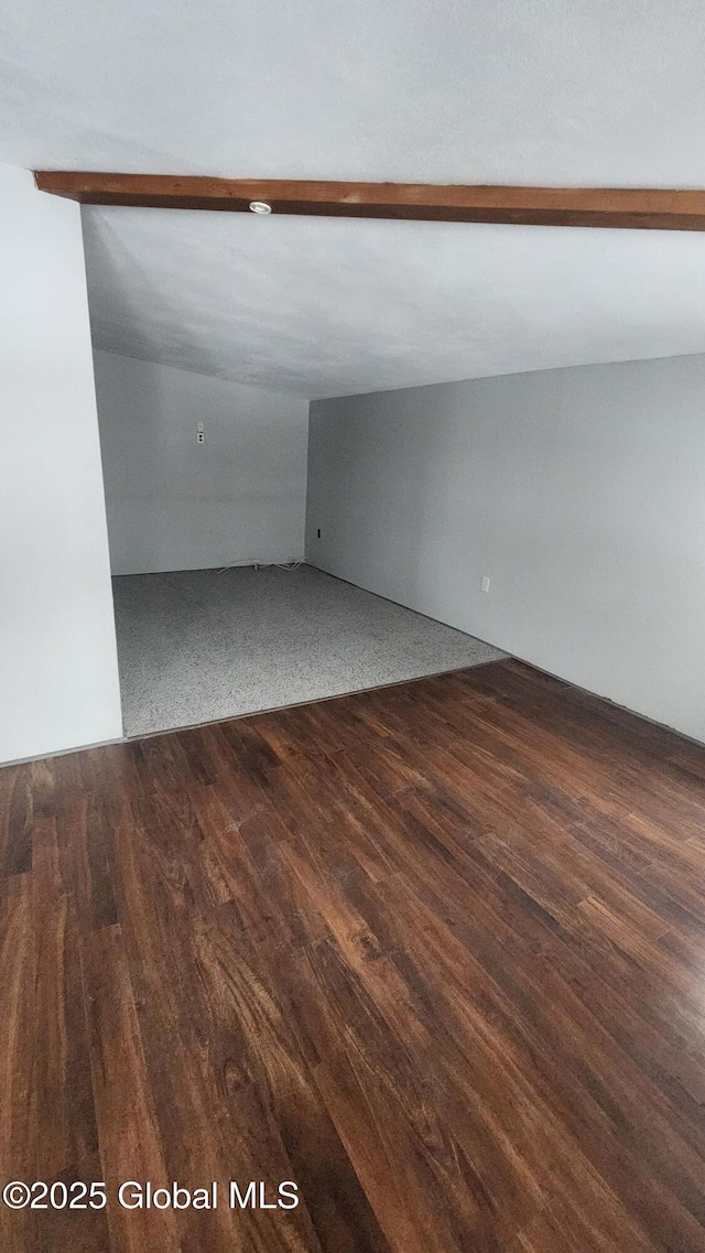 spare room with vaulted ceiling with beams and dark wood-type flooring