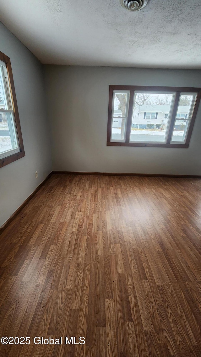 unfurnished room with a textured ceiling and hardwood / wood-style floors