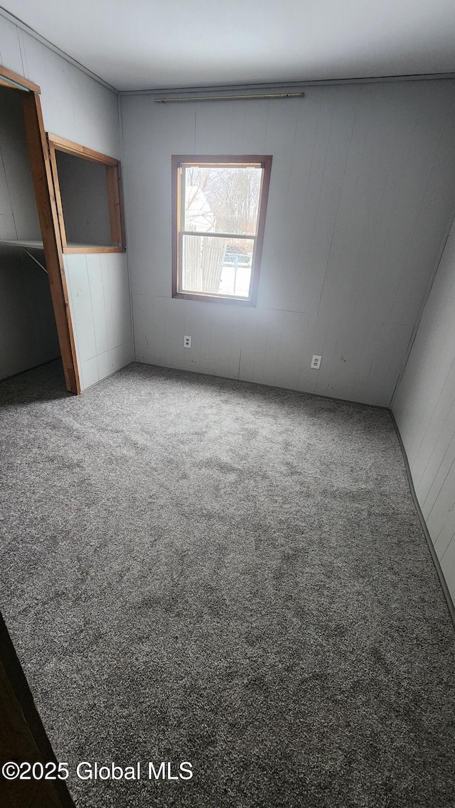 unfurnished bedroom with carpet floors and wood walls